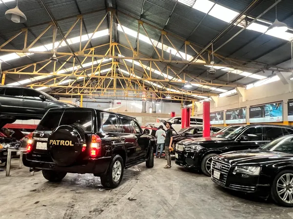 Audi sedans and a Nissan Patrol parked inside the Autobahn Solutions workshop, Dhaka