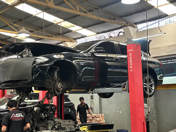 Technician working on the undercarriage of a car raised on a lift at Autobahn Solutions, Dhaka