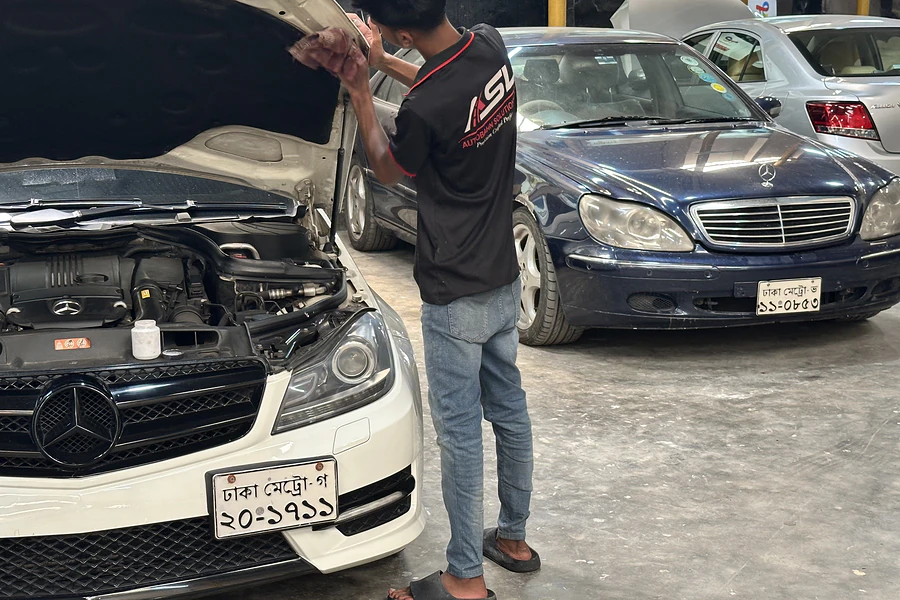 Autobahn Solutions technician working in the engine bay of a Mercedes-Benz