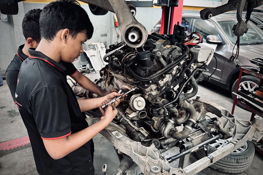 Autobahn Solutions technicians working on an engine removed from a car for a full rebuild